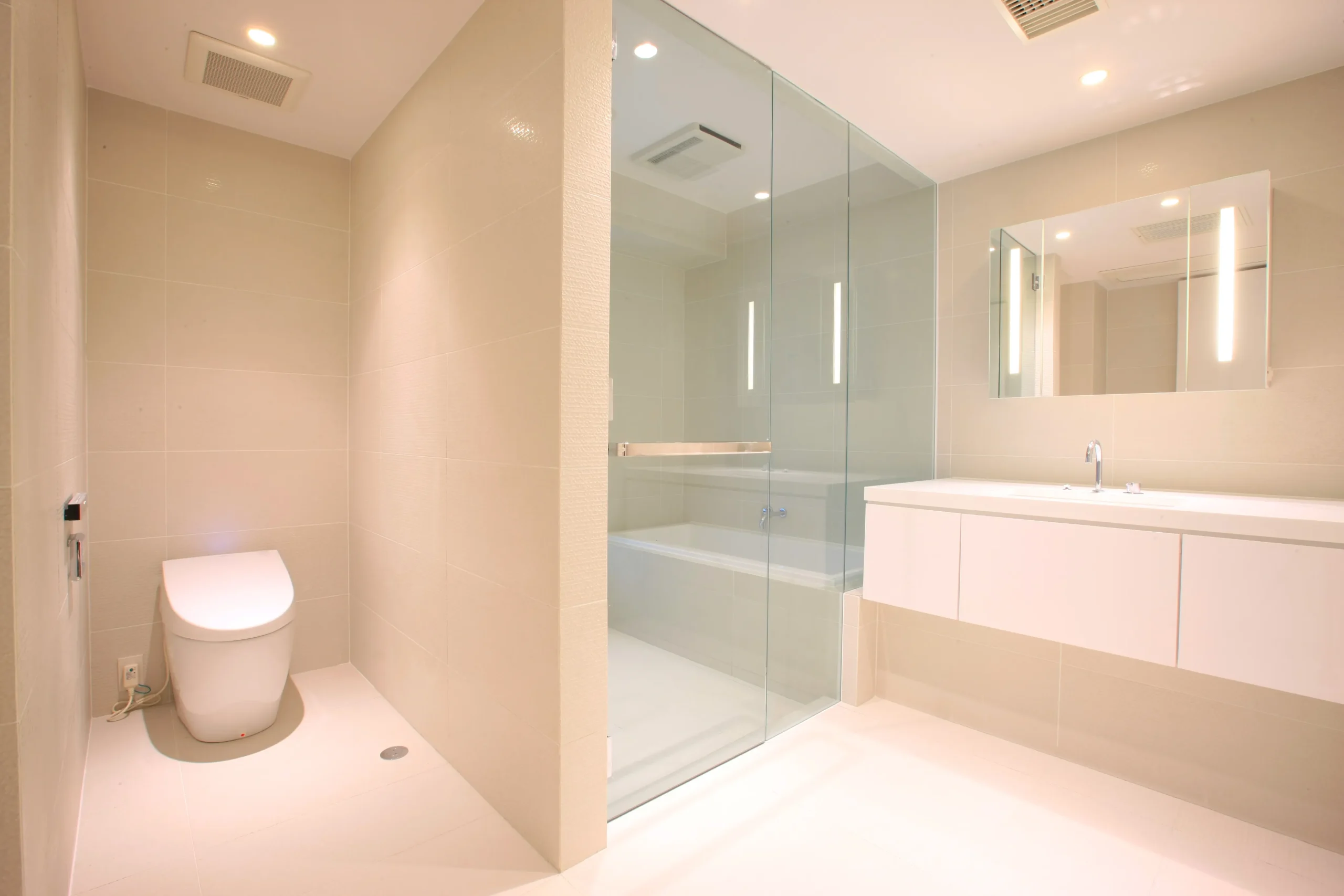 洗面室と浴室を透明な強化ガラスで仕切り、床の素材を統一することで、海外のホテルのような広がりと連続性を持たせた「ホテルライク」な浴室